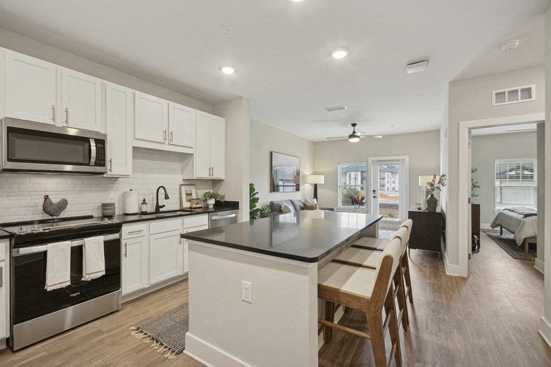 A modern kitchen with white cabinets and a black countertop.