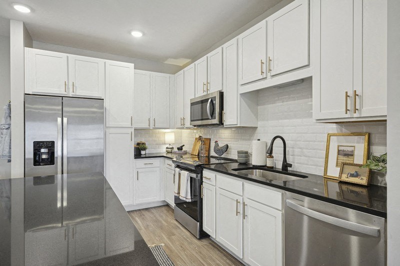 A modern kitchen with white cabinets and stainless steel appliances.