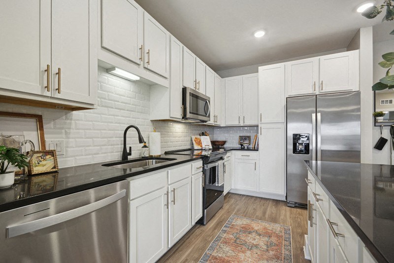 A modern kitchen with white cabinets and stainless steel appliances.