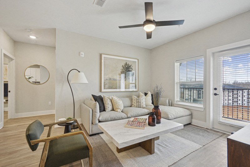 A living room with a couch, a chair, a coffee table, and a ceiling fan.