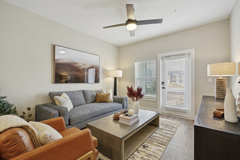 A living room with a grey couch, a brown leather chair, a coffee table, and a painting on the wall.