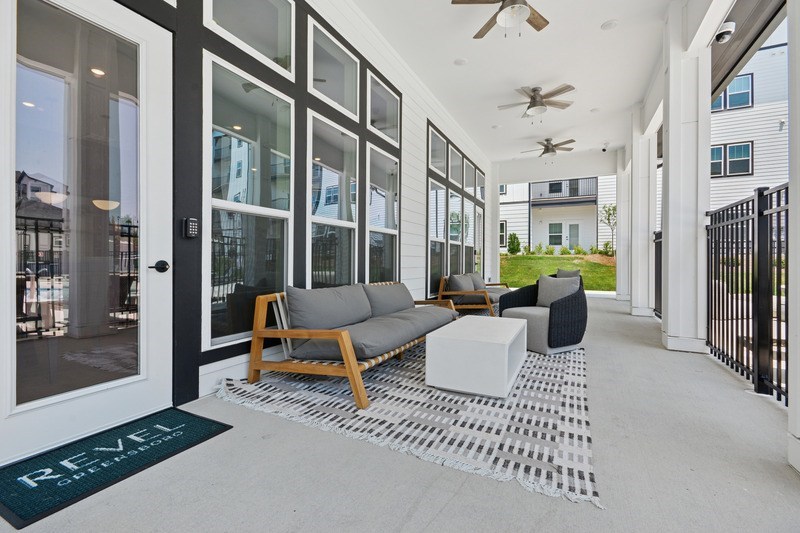 A patio with a couch, chairs, and a rug with the word REVEL on it.