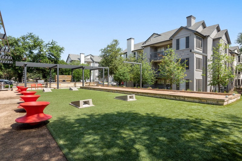 a grassy area with chairs and a pergola in front of a building