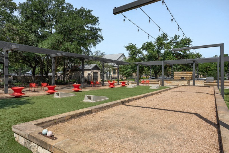 a park with grass and a gravel path with a pavilion in the background
