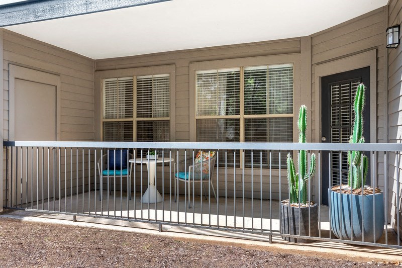 a balcony with a cactus and two chairs
