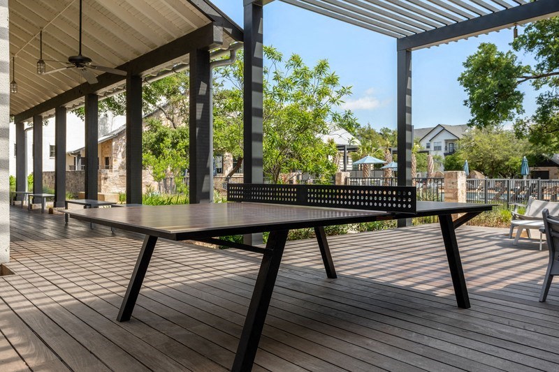 an outdoor patio with a ping pong table and a pergola