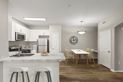 A kitchen with white cabinets and a dining table next to it.