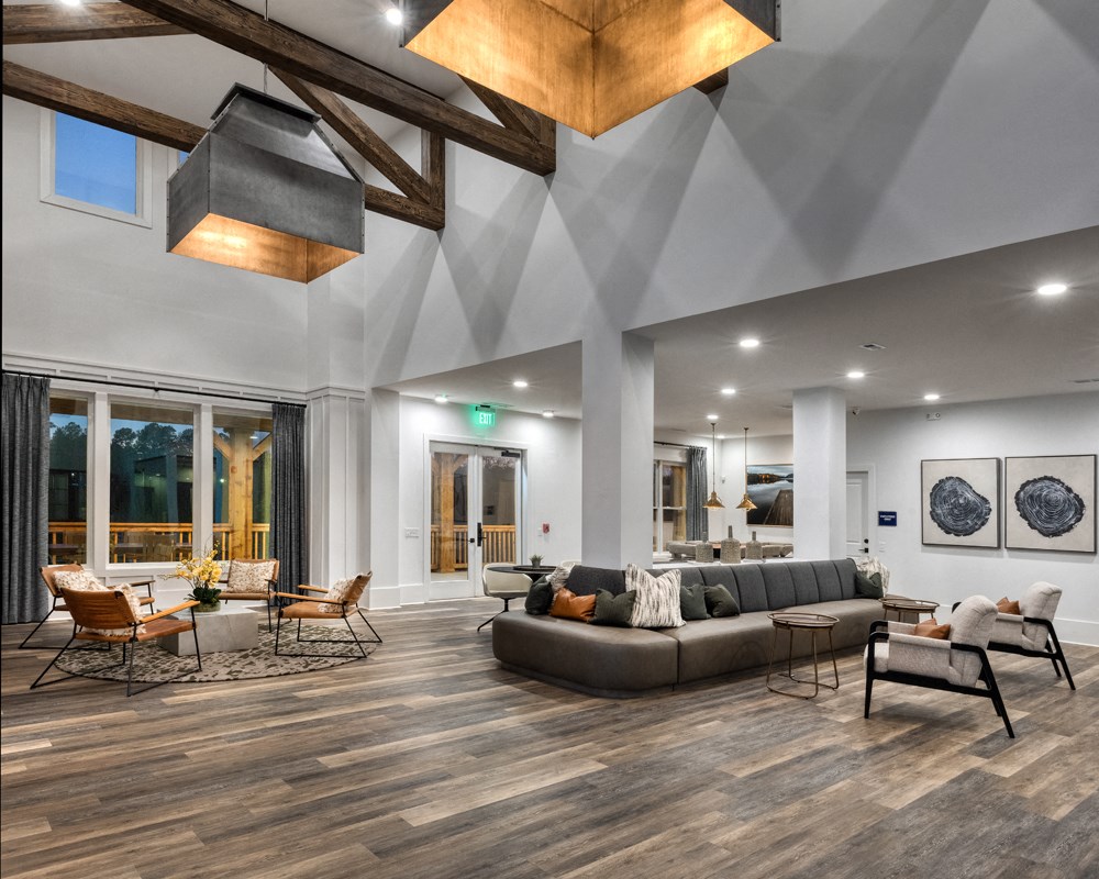 A modern living room with a grey sofa, wooden beams, and a large window.