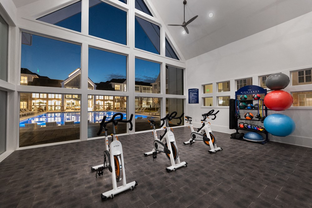 A gym with exercise equipment and a view of a pool.