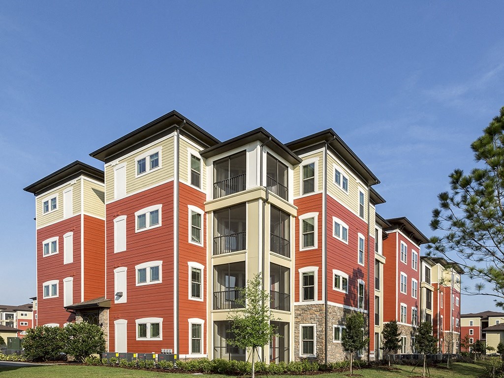 A red and beige apartment building with a clear blue sky in the background.
