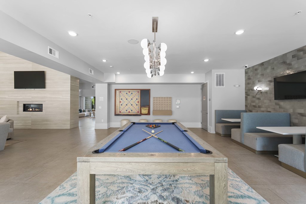 A pool table is in the middle of a room with a fireplace and a TV.