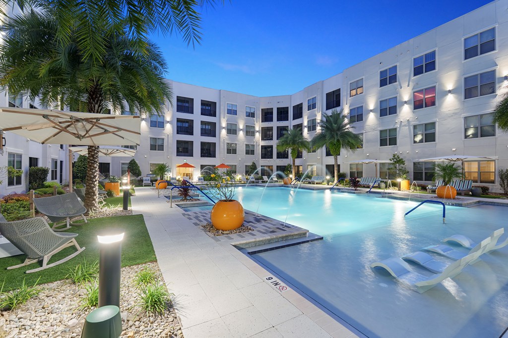 A large swimming pool surrounded by palm trees and lounge chairs.