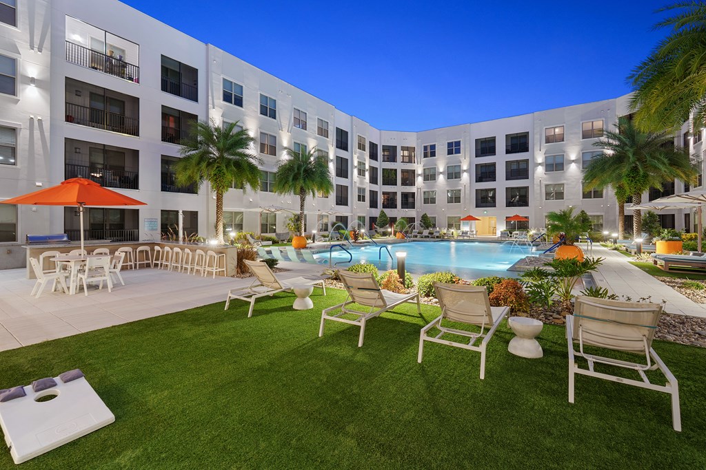 A poolside area with chairs and umbrellas in front of a building.