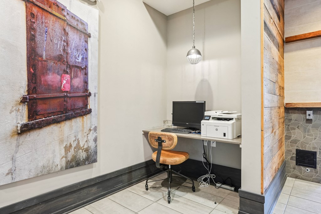 an office with a desk with a computer and a painting on the wall