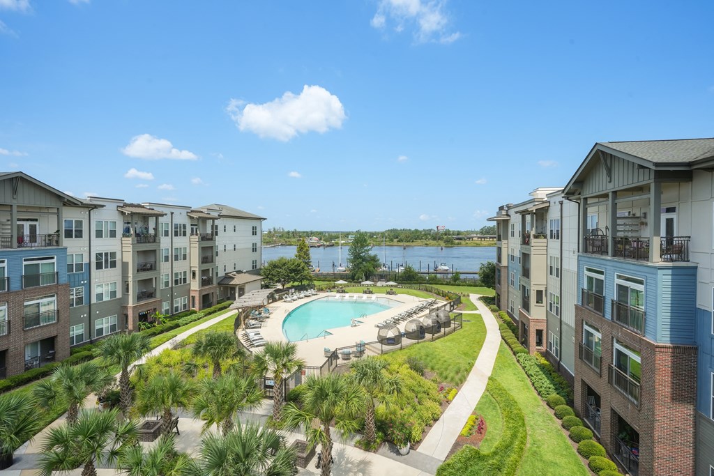 an aerial view of an apartment complex with a swimming pool and a lake