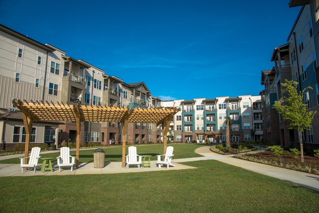 an exterior view of an apartment building with a picnic area and chairs