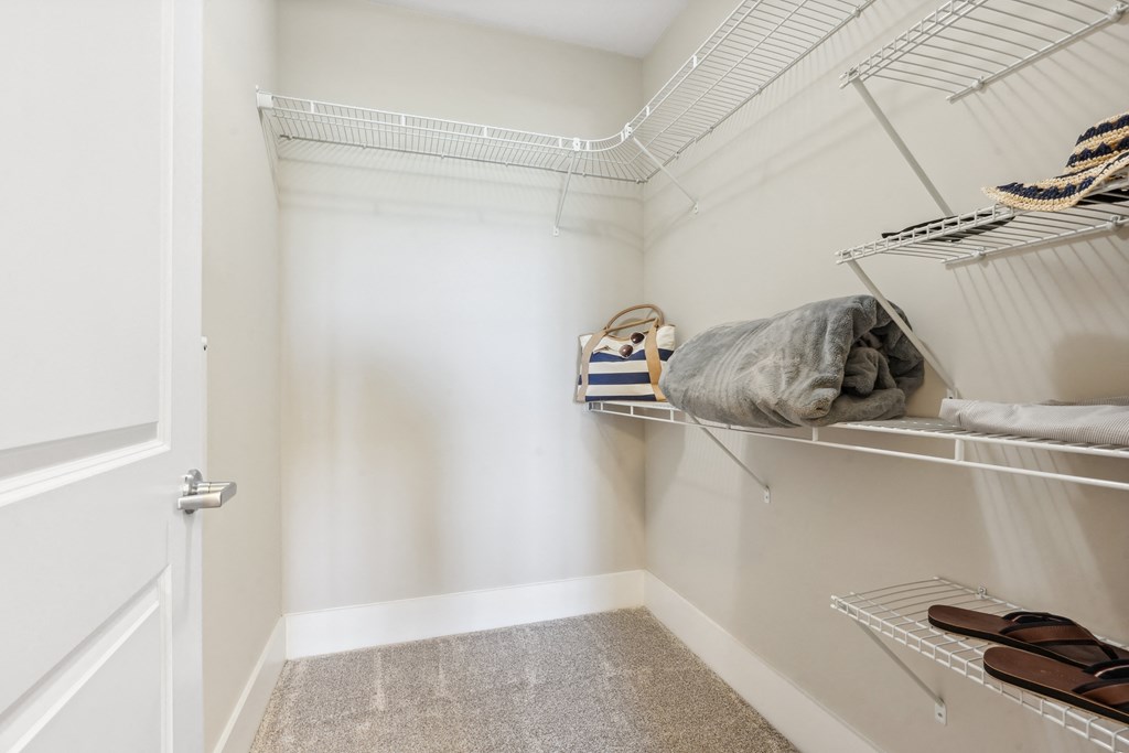 a walk in closet with white walls and shelves with clothes and shoes