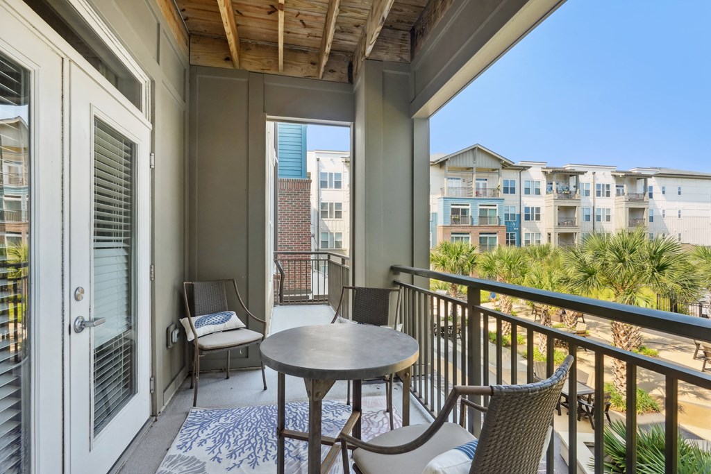 two chairs and a table on a balcony with a beach view