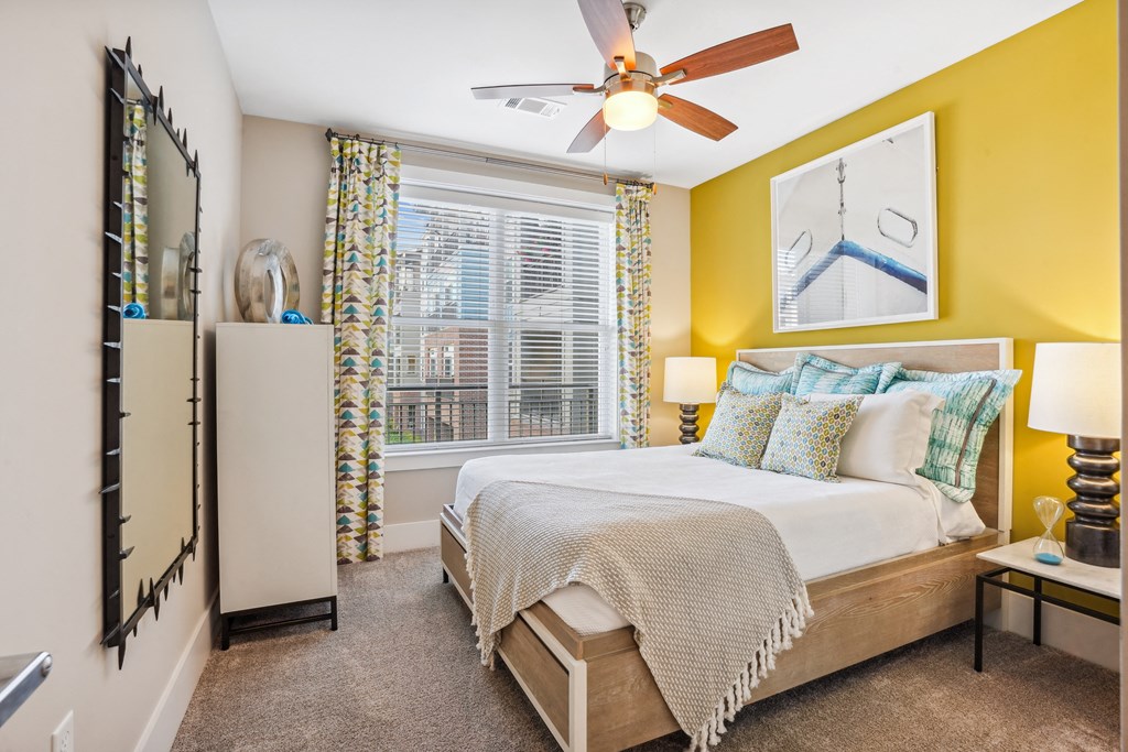 a bedroom with a large window and a ceiling fan