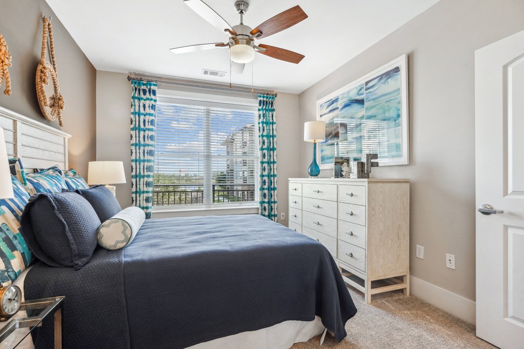 a bedroom with a large window and a ceiling fan