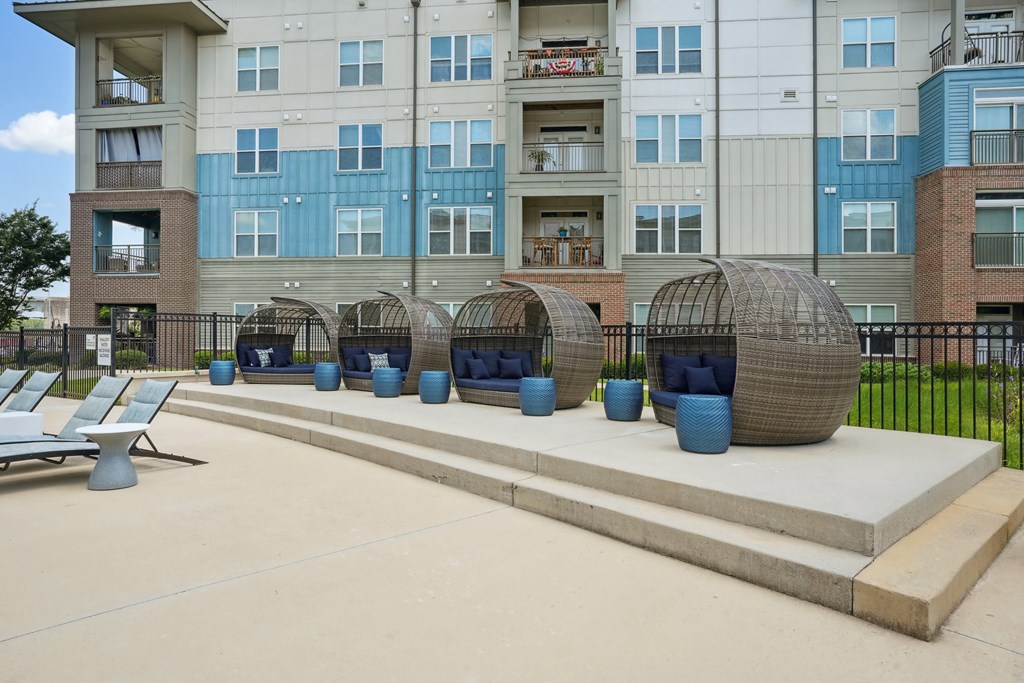 an outdoor lounge area with chairs and tables at an apartment building
