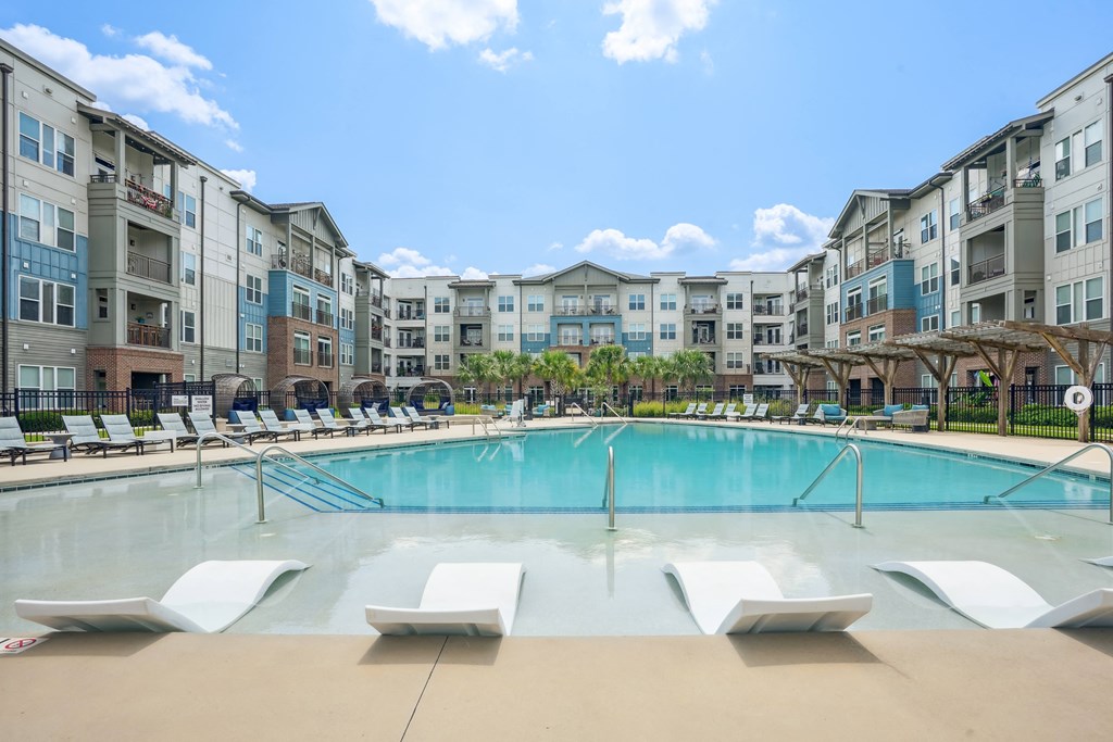 an outdoor pool with lounge chairs and an apartment building