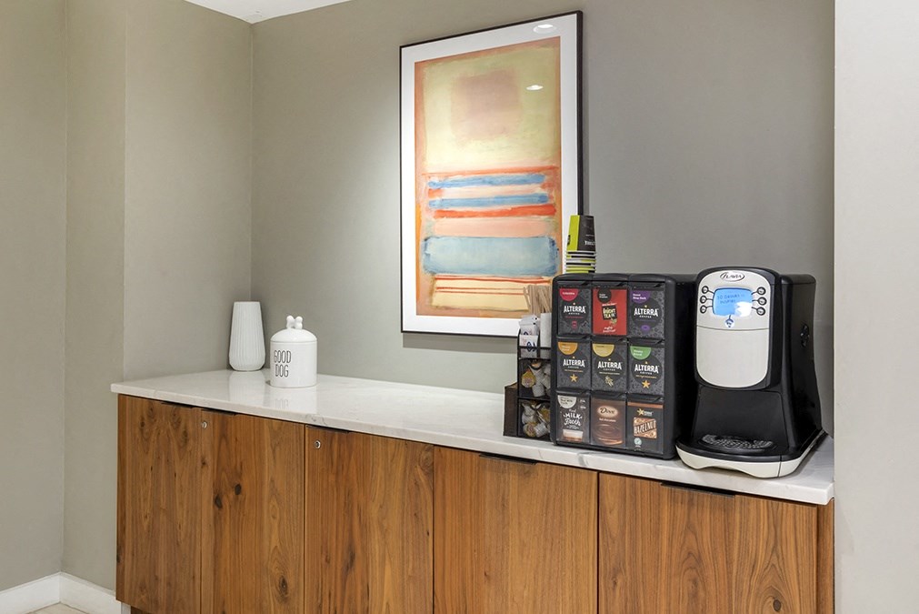 a kitchen counter with a coffee maker and a painting on the wall