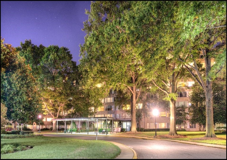 a city street at night with trees and a building