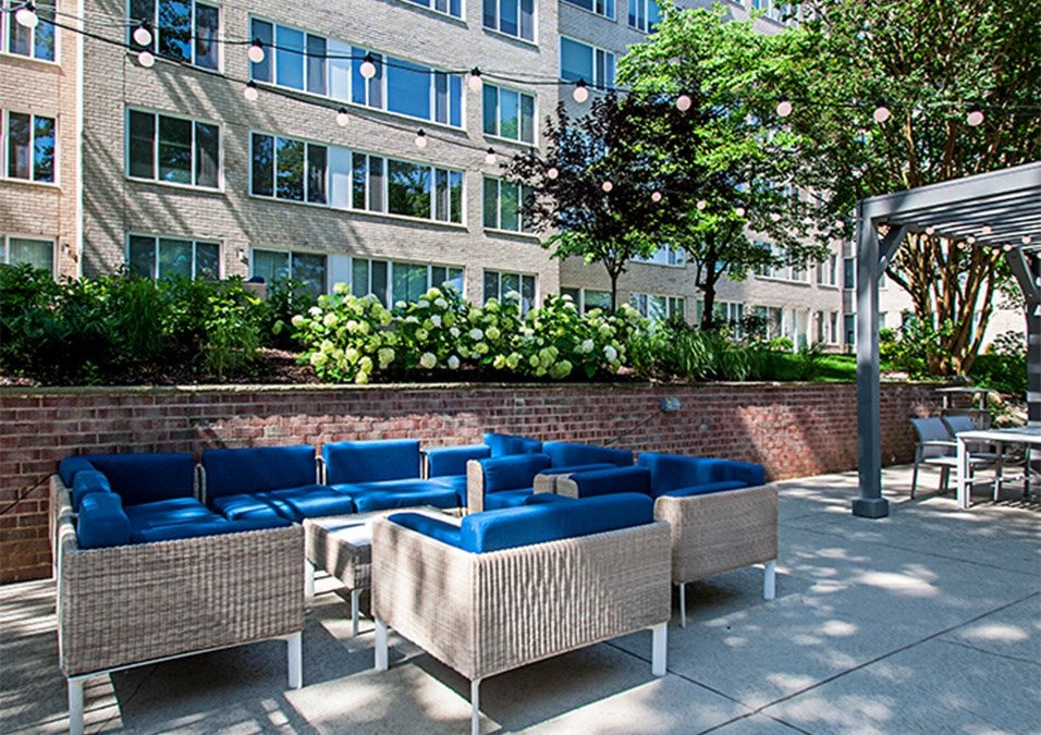 a patio with blue couches and chairs in front of a building
