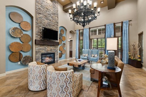 A living room with a stone fireplace and a chandelier.
