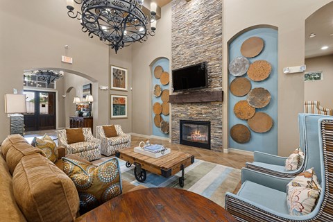 A living room with a stone fireplace and a chandelier.