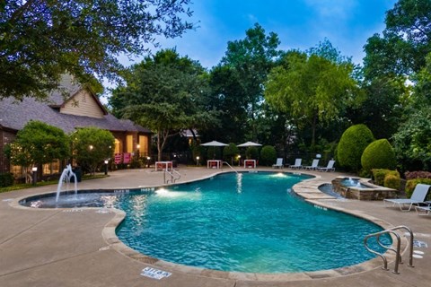 A swimming pool surrounded by trees and a house.