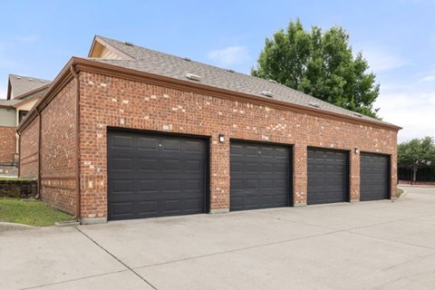 A red brick building with three black garage doors.