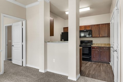 A kitchen with white cabinets and a black fridge.