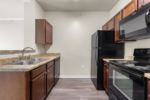 A kitchen with a black refrigerator and stove top oven.