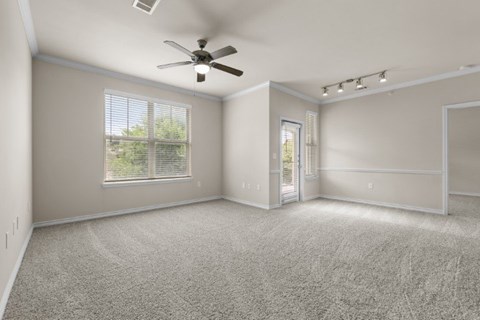 A spacious room with a ceiling fan and carpeted floor.