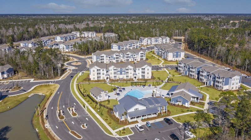 an aerial view of an apartment complex with a lake and a road