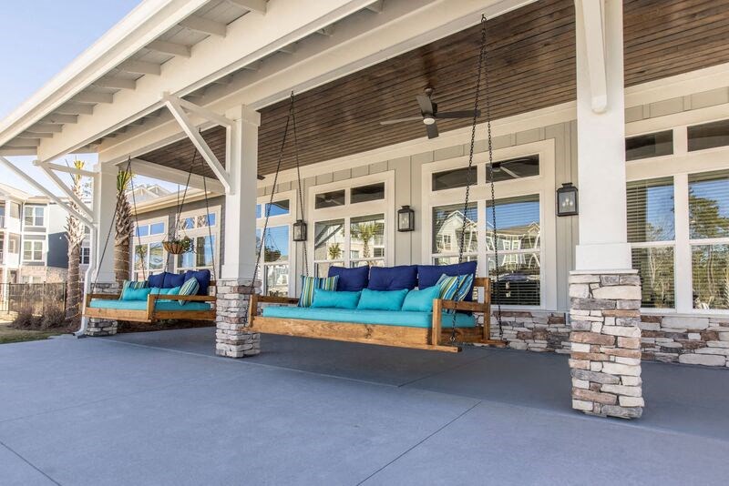 a porch with blue couches and chairs hanging from a porch