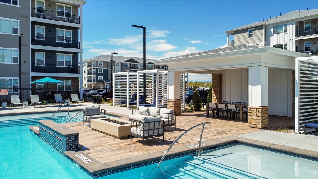 a swimming pool and a building with a patio and chairs