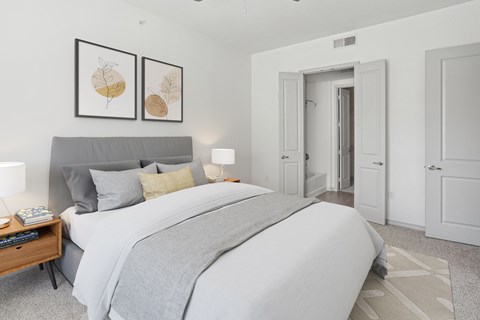 A bedroom with a large bed and two framed pictures on the wall.
