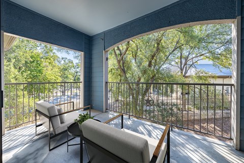 A balcony with a chair and a table with a potted plant on it.