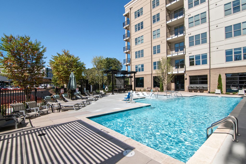 our apartments have a large swimming pool with lounge chairs and an apartment building