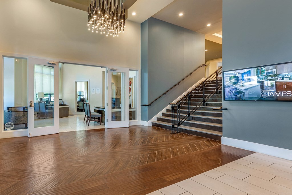a lobby with a staircase and a tv on the wall