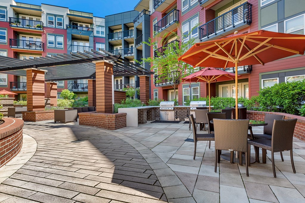 a patio with tables and umbrellas in front of an apartment building