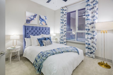 a bedroom with a bed and a window with blue and white curtains