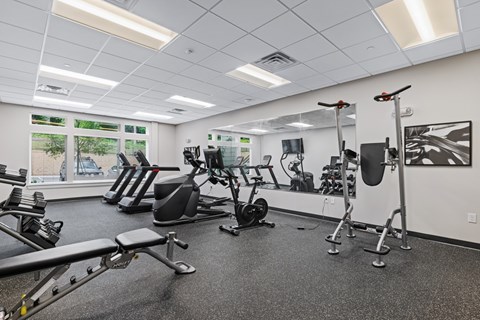 A gym with a variety of equipment including treadmills, weights, and exercise machines.
