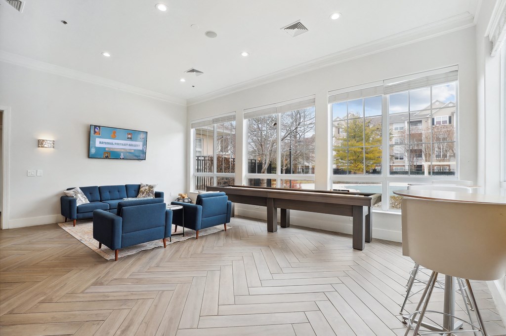 a living room with couches and a pool table in front of a window