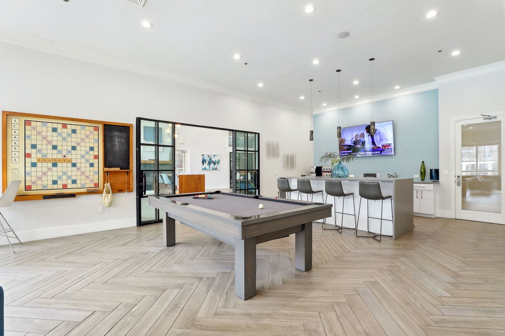 a game room with a pool table and a bar with a tv