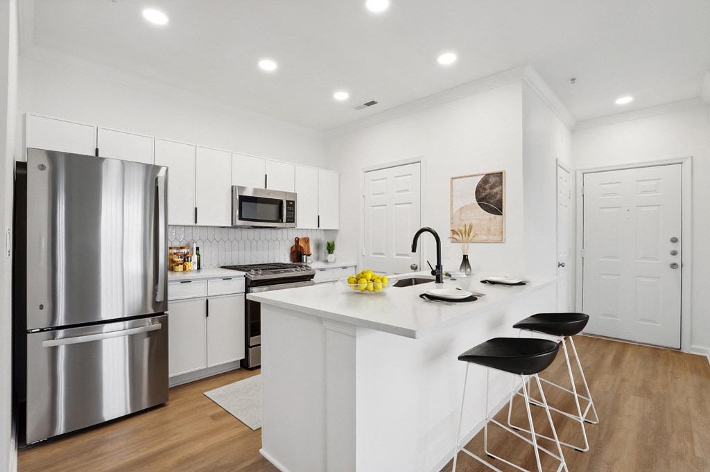 a white kitchen with a large island and stainless steel appliances