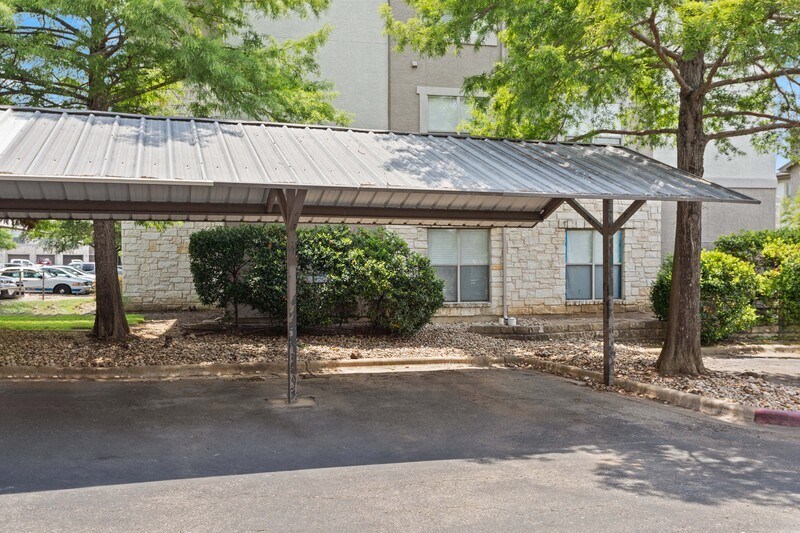 a covered parking lot with a stone building in the background